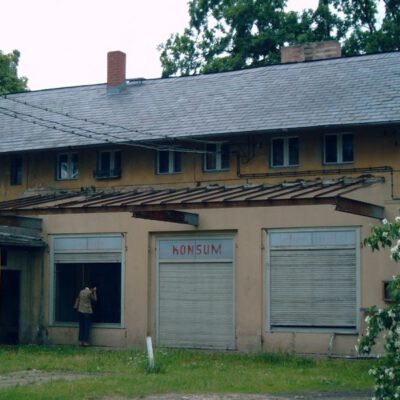 Alte Aufnahme in Farbe eines Konsumgebäudes - eine Person lugt in ein Fenster hinein: Der verlassene Kutschstall nach 1990 - Foto: Privatbesitz