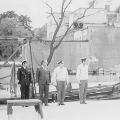 S/W Foto am Hafen: 4 Männer in Reihe vor Boots-Slip-Anlage am Hafen: Appell mit der Villa Hagen im Hintergrund - Foto: Privatbesitz