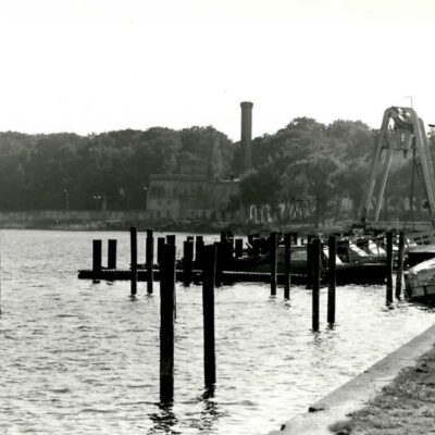 S/W Foto am Wasser mit Pfählen: Aufnahme der Grenztruppen vom Bootshafen der Grenztruppen mit Postenhaus (markiert) und Meierei - Foto: BSTU, MfS BV Pdm AU 2688/87 Bild 2